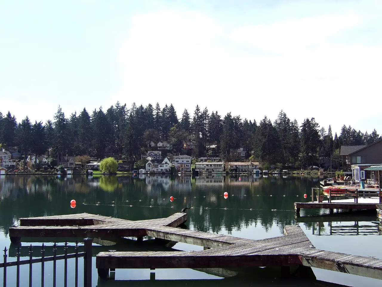 Boat docks on Lakewood Bay of Oswego Lake, lined with evergreen trees