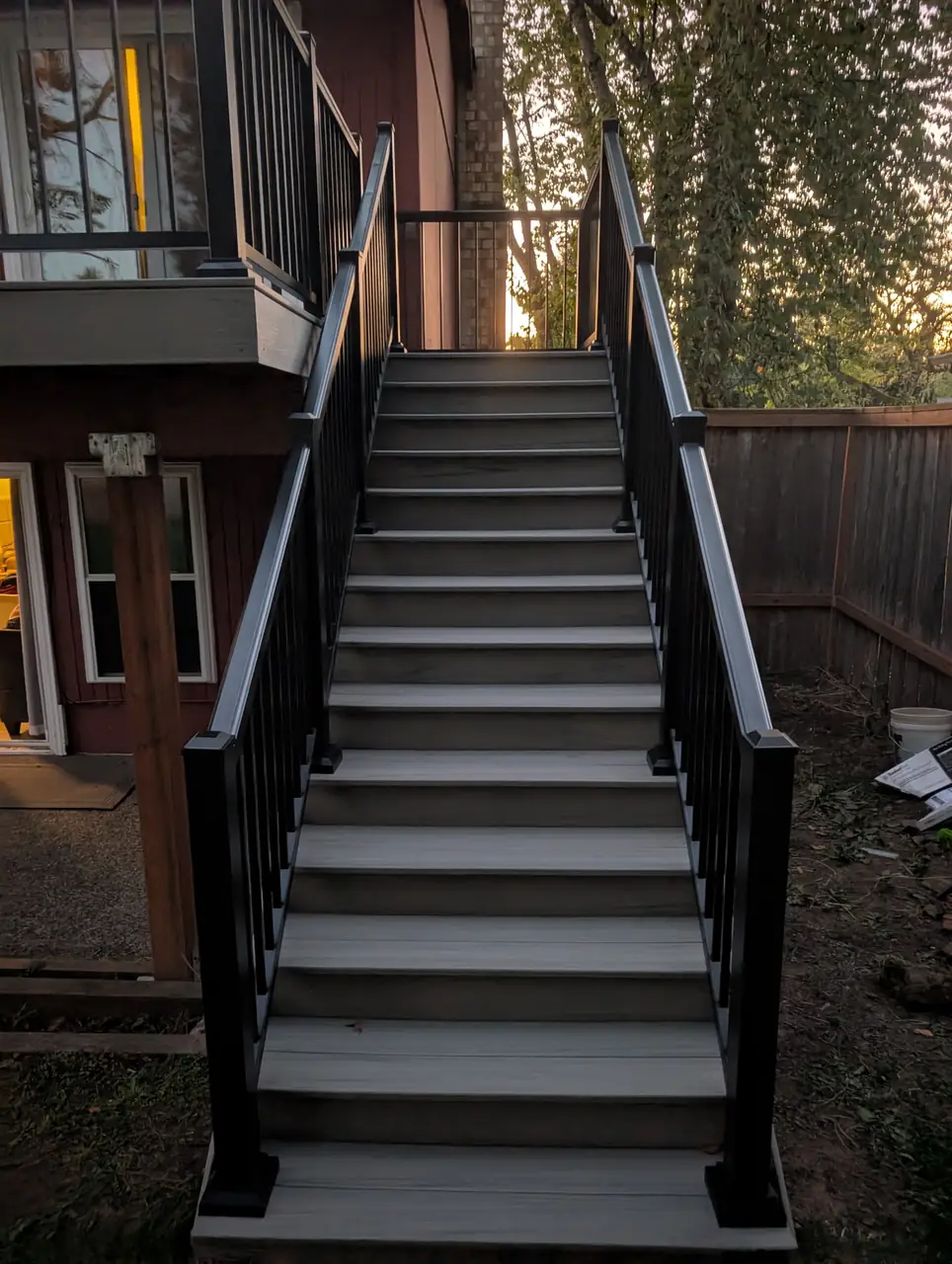 Composite deck stairs with black aluminum railings leading up to a second-story deck