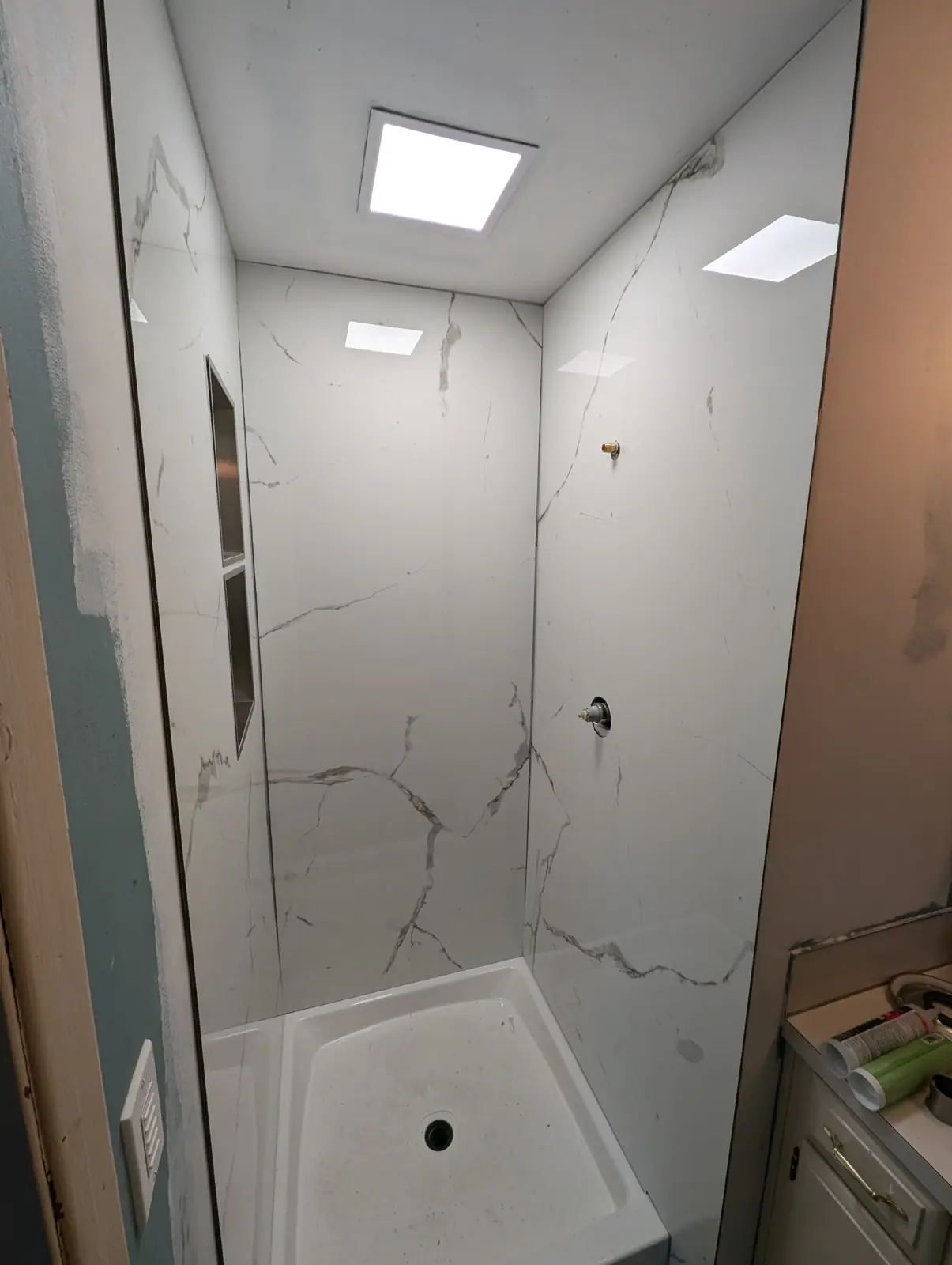 Marble-look shower wall panels installed around a new shower base, before trim